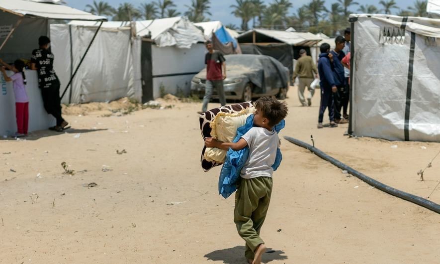 一名男孩在加沙流离失所者营地搬运物品。