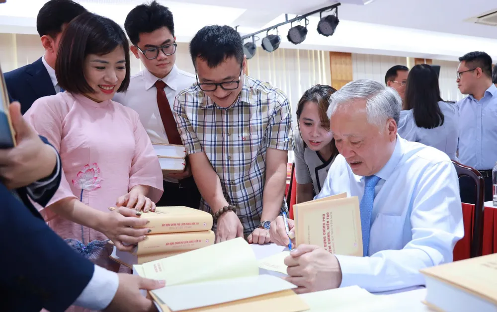 GS-TS Nguyễn Hòa Bình, nguyên Phó Thủ tướng Thường trực Chính phủ ký tặng sách cho bạn đọc. Ảnh: NGUYỄN CHẮT
