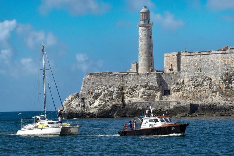 3月28日，一艘向古巴运送人道主义援助物资的船只（左）在引航船的指引下驶入哈瓦那港。新华社照片