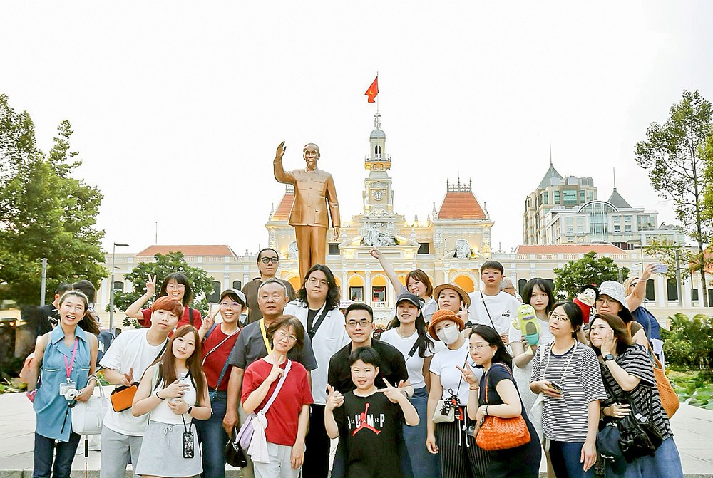 众多游客在胡志明市人委会办事处前的胡志明主席雕像下拍照留念。图：勇芳