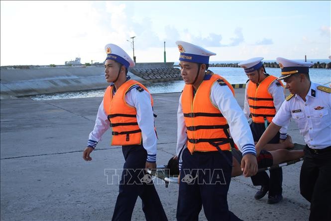 双子西岛战士与医护人员接诊在海上作业时遇险的两名渔民。图源：越通社