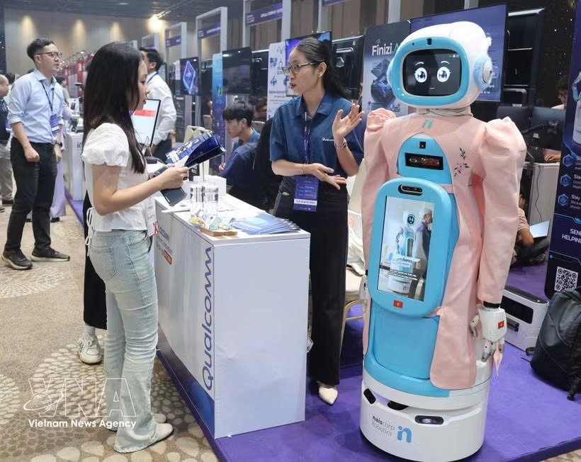 参观者在Qualcomm展台了解老年人护理机器人模型。图自越通社