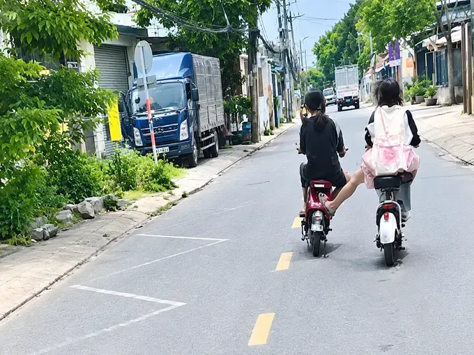 骑2辆电动自行车在路上蛇行穿梭，并在卡车前方切道的一伙少年。图自HT