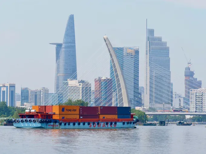 集装箱驳船在西贡河上行驶，途经巴逊桥区域，为胡志明市注入蓬勃的贸易活力。图:黄雄