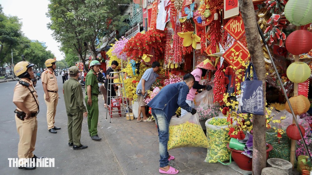 交警力量和堤岸公安公安要求各商铺搬迁占用人行道的货物。图：《青年报》