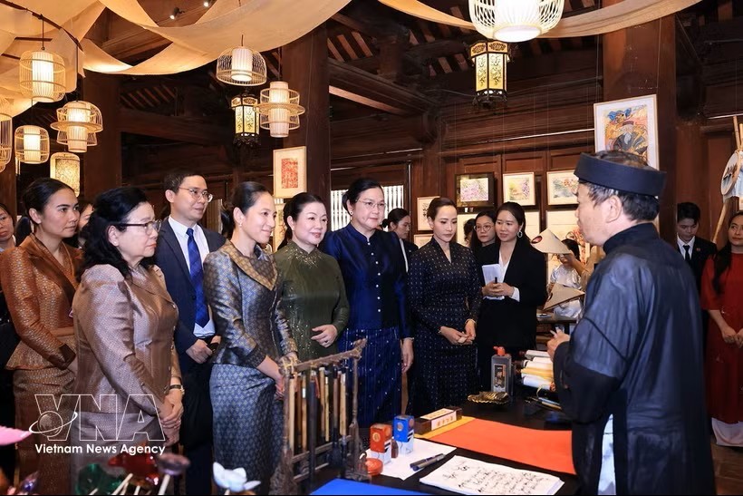 越南政府总理黎明兴夫人与老柬泰三国总理夫人听取越南书法艺术的介绍。图：越通社