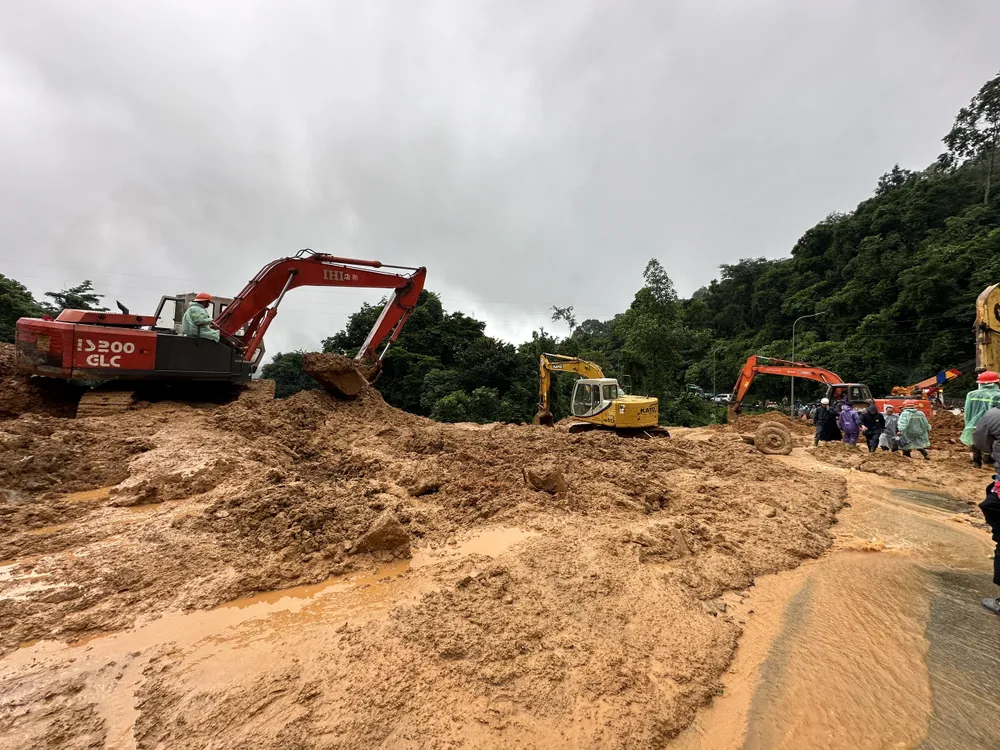 Hàng chục nhân lực cùng 6 chiếc máy múc đang khẩn trương dọn dẹp khu vực sạt lở. Ảnh: ĐOÀN KIÊN