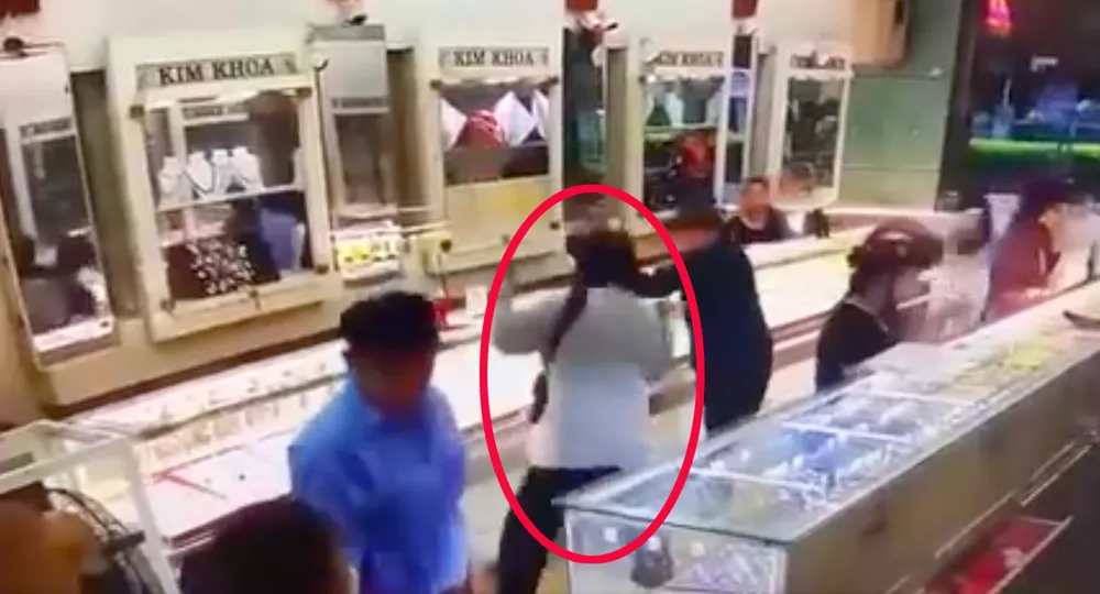 Một trong hai đối tượng sau khi uy hiếp bảo vệ đã dùng búa phá tủ, cướp tài sản. Ảnh chụp từ camera