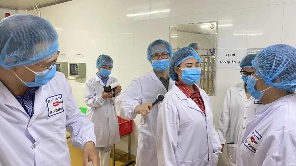 Để vào bên trong khu vực giết mổ, pha lóc thịt heo, toàn bộ trang phục của khách và công nhân đều phải sát trùng, khử khuẩn, không để rơi một sợi tóc. Ảnh: VĂN PHÚC