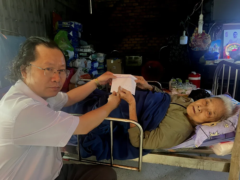 Đại diện Báo Sài Gòn Giải Phóng trao tiền bạn đọc hỗ trợ cụ bà Vũ Thị Tân.