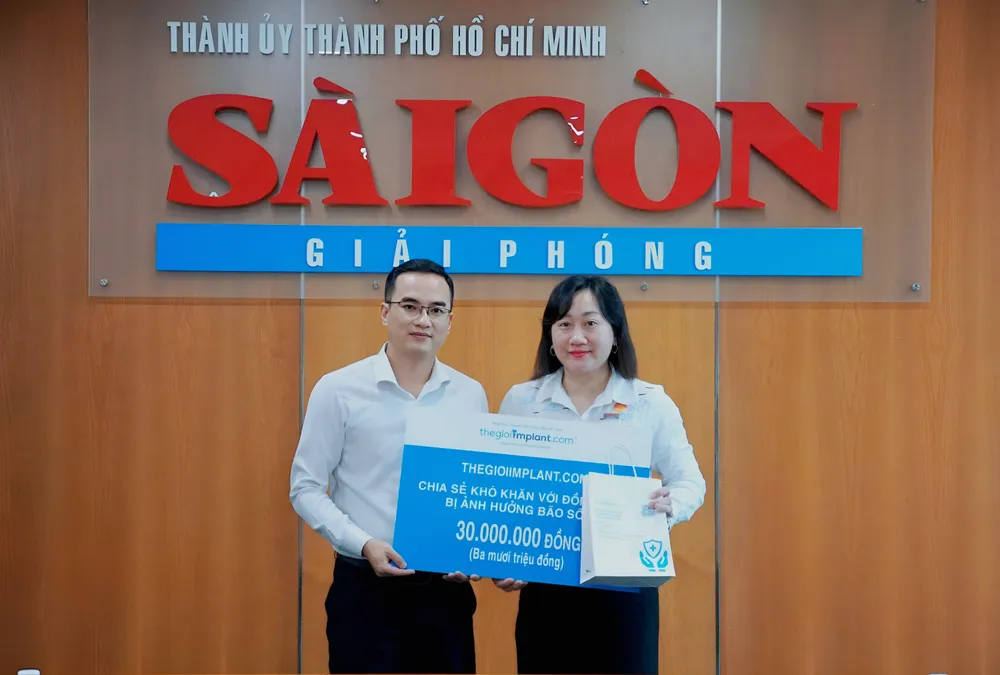 Bà Bùi Thị Hồng Sương, Phó tổng Biên tập Báo Sài Gòn Giải Phóng tiếp nhận 30 triệu đồng chia sẻ khó khăn với đồng bào bị ảnh hưởng bão số 10 (Bualoi) từ ông Nguyễn Thanh Hiền, Giám đốc điều hành Thegioiimplant.com Ảnh: VIỆT NGA 