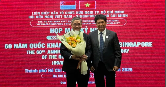 越新友好协会代表（右）向新加坡驻胡志明市总领事彭迪成赠送献花。图自《西贡解放报》 