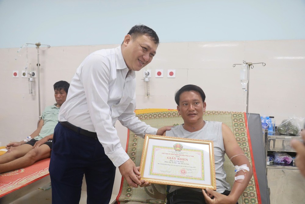 阮文辉主席向正在李山特区军民医疗中心接受治疗的黎文生颁发奖状。 