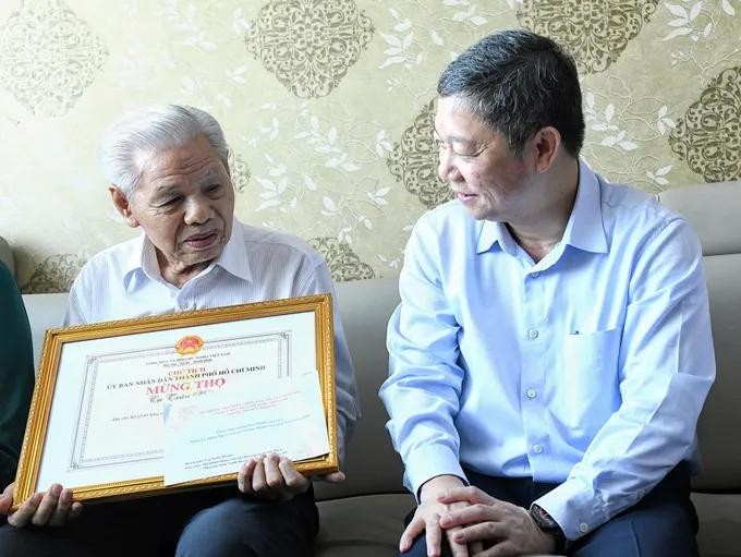 胡志明市市委宣教与民运处主任杨英德亲切问候陈皖长者的身体状况。