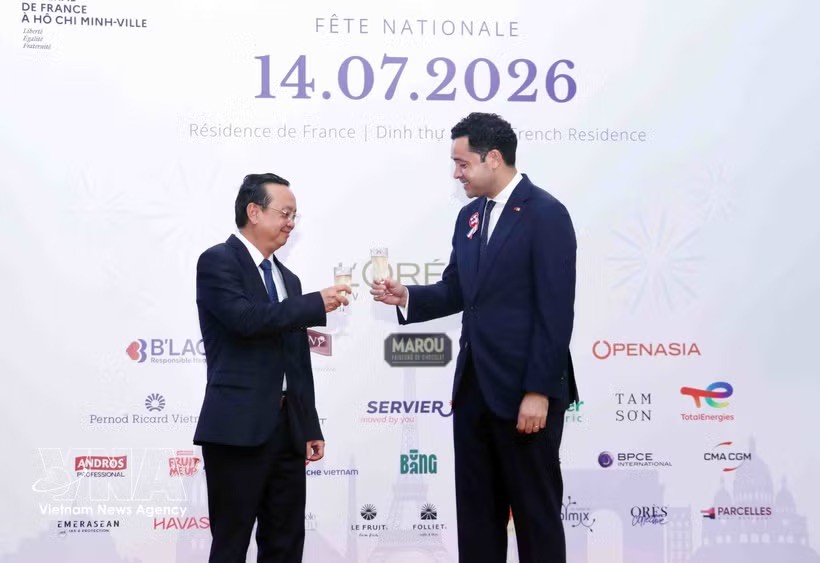 胡志明市人委会副主席裴明盛（左）与法国驻胡志明市总领事艾蒂安·拉纳瓦松举杯祝贺法国国庆。