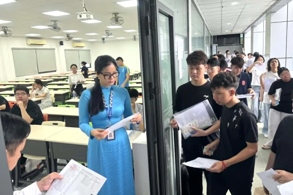 Cán bộ coi thi gọi thí sinh vào phòng thi tại điểm thi Trường ĐH Công nghiệp TPHCM - Ảnh: THANH HÙNG