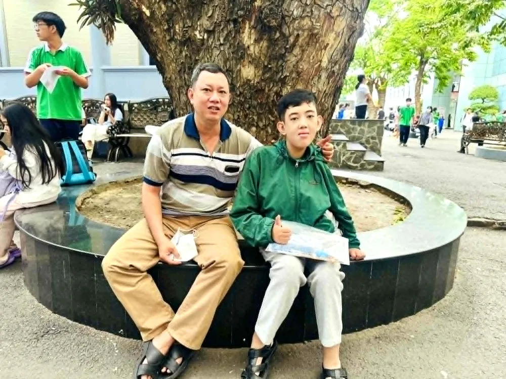 Thí sinh Nguyễn Trân Khiêm (Trường THPT Tây Thạnh) bị khuyết tật nặng hai chân được cha đưa đi thi và ngồi chờ lực lượng thanh niên hỗ trợ đưa lên phòng thi .jpg