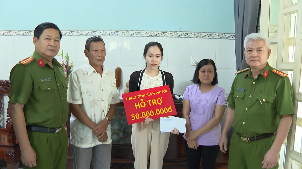 Đại tá Lâm Văn Long (bên trái), Phó Giám đốc Công an tỉnh Bình Phước trao trợ cấp đột xuất của UBND tỉnh cho gia đình anh Hoàng Nhật Tiến, bảo vệ dân phố phường Hưng Long, thị xã Chơn Thành