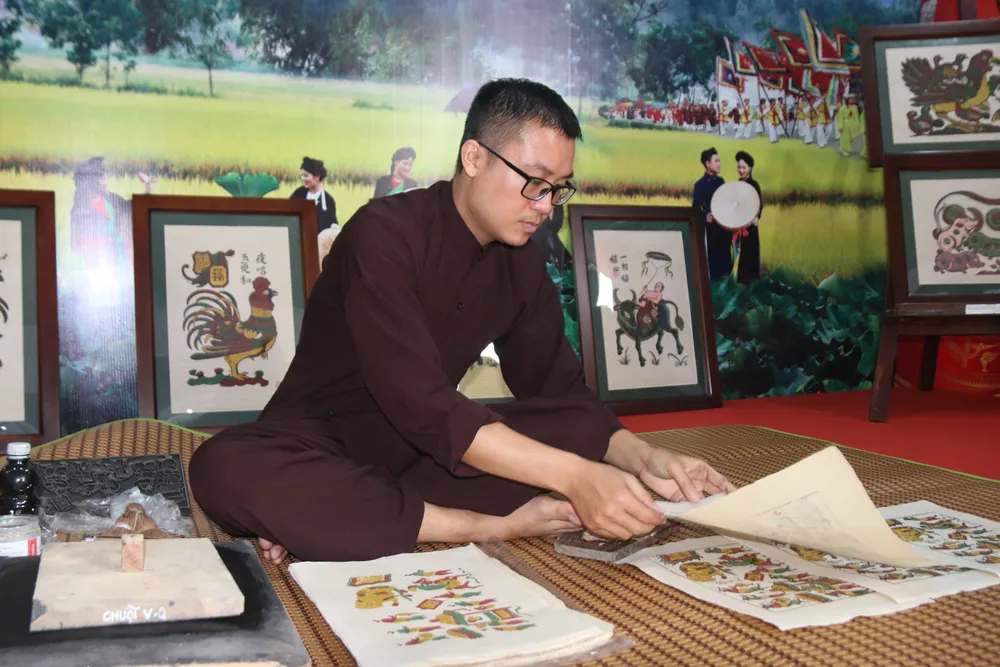 Du khách thích thú xem nghệ nhân biểu diễn công đoạn in tranh Đông Hồ của tỉnh Bắc Ninh