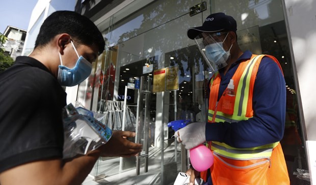 A shopper has his hands sprayed with sanitiser before entering a shop in Cambodia (Photo: khmertimeskh.com)