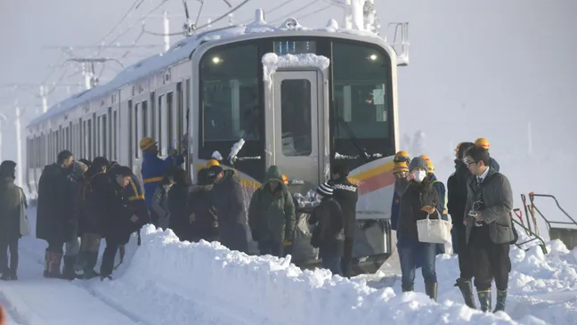 Hành khách ra khỏi xe lửa sáng 12-1-2018 sau khi phải qua đêm trên đoàn xe lửa bị mắc kẹt do tuyết rơi dày ở TP Sanjo, tỉnh Niigata, Nhật Bản. Ảnh: KYODO