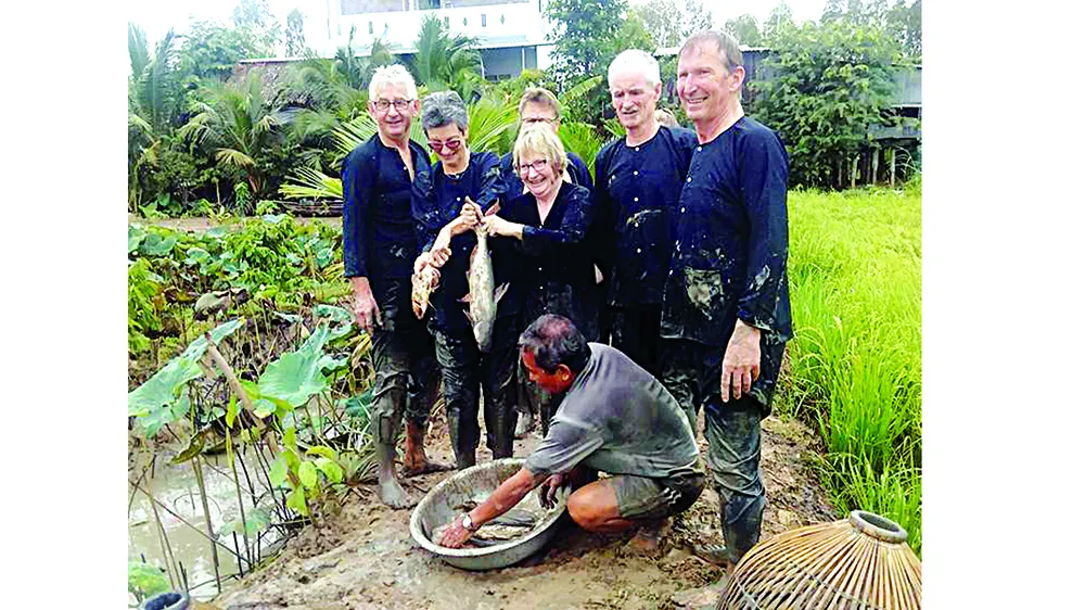 Ông Bé Tư bắt cá đồng bằng nom cùng du khách phía sau ruộng trong sen kết hợp nuôi cá