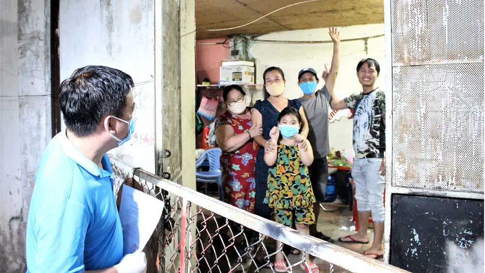 Ông Phạm Trung Kiên (trái), Chủ tịch UBND phường 7 quận Gò Vấp, đến từng nhà  trao giấy chứng nhận hoàn thành thời gian cách ly