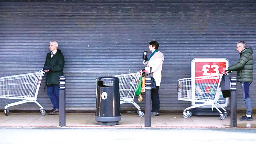 Người dân Anh giữ khoảng cách khi xếp hàng vào siêu thị