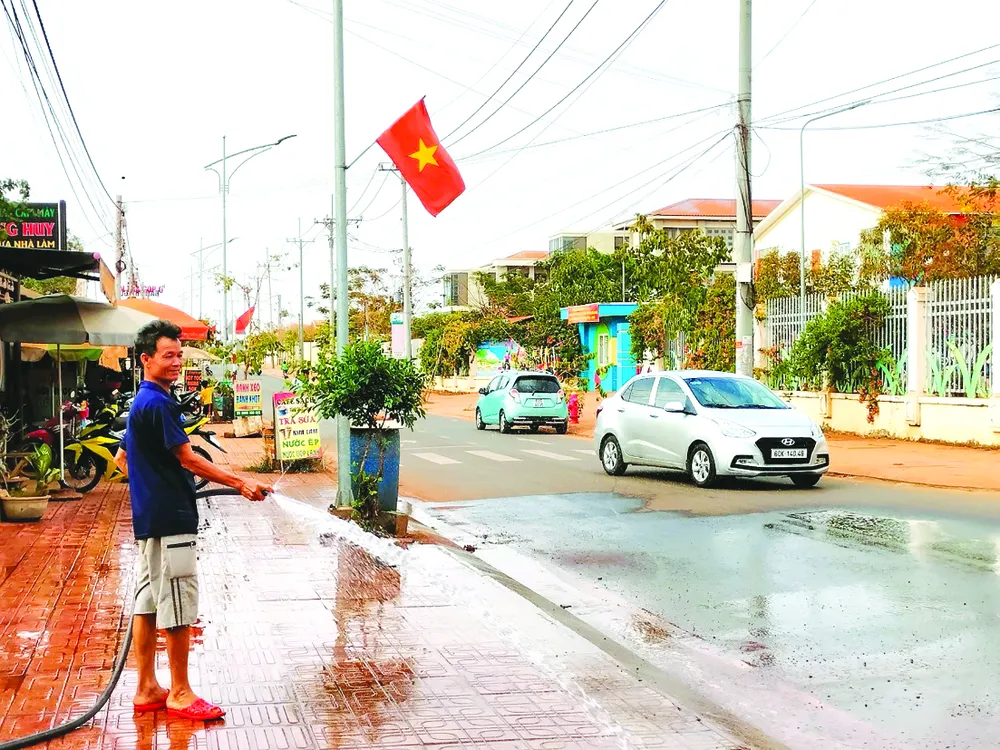 Người dân ấp 1, xã Bình Sơn, huyện Long Thành xịt nước nhằm hạn chế bụi bẩn bay vào nhà