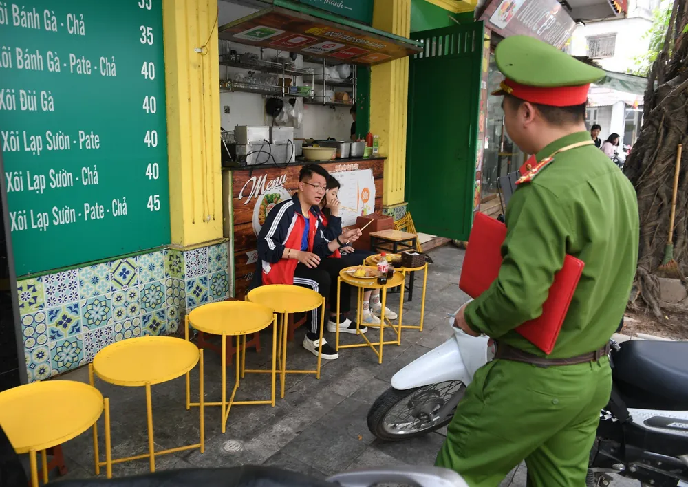 Lực lượng công an nhắc nhở một trường hợp lấn chiếm vỉa hè. Ảnh: VIẾT CHUNG