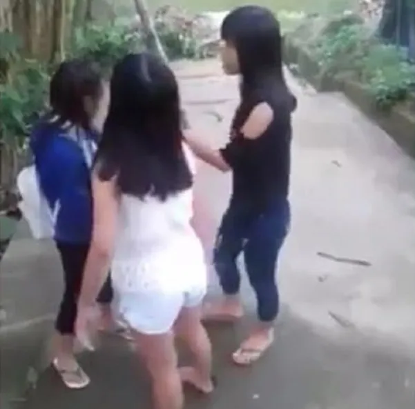 Hai nữ sinh mặc áo đen và áo trắng lao vào đánh bạn nữ mặc áo xanh.