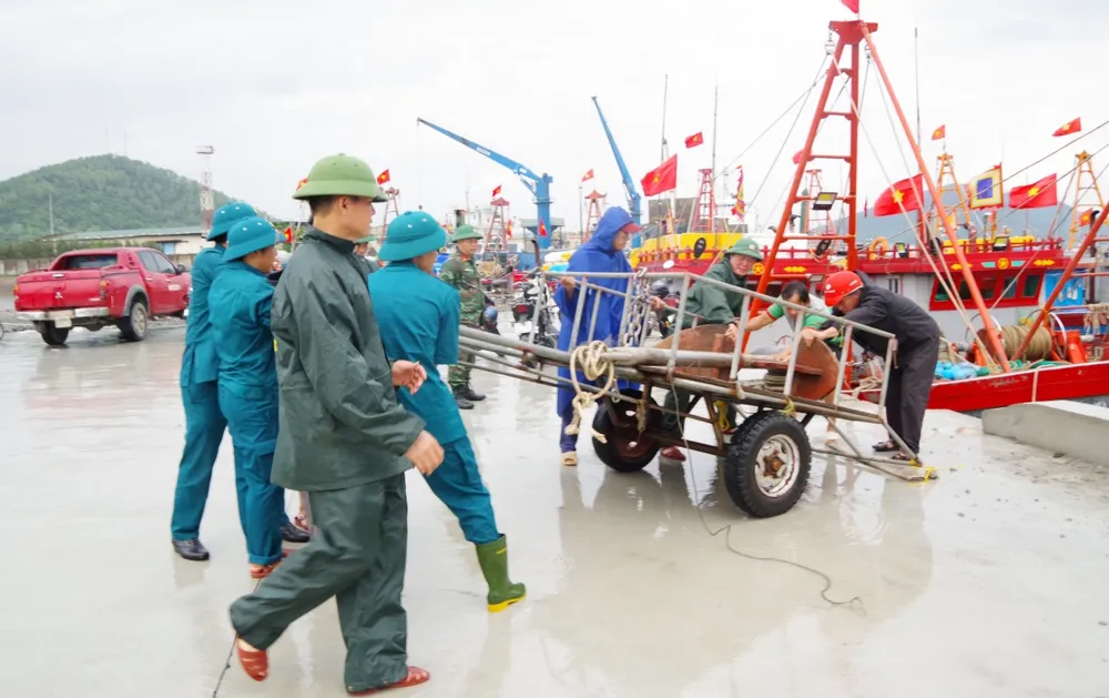 Cán bộ, chiến sĩ, bộ đội biên phòng, dân quân tự vệ Bộ CHQS tỉnh Nghệ An hướng dẫn và giúp ngư dân neo đậu tàu thuyền