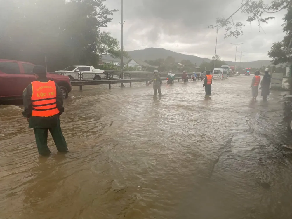 Lực lượng chức năng ứng trực hướng dẫn người và phương tiện lưu thông qua đoạn Quốc lộ 1A bị ngập