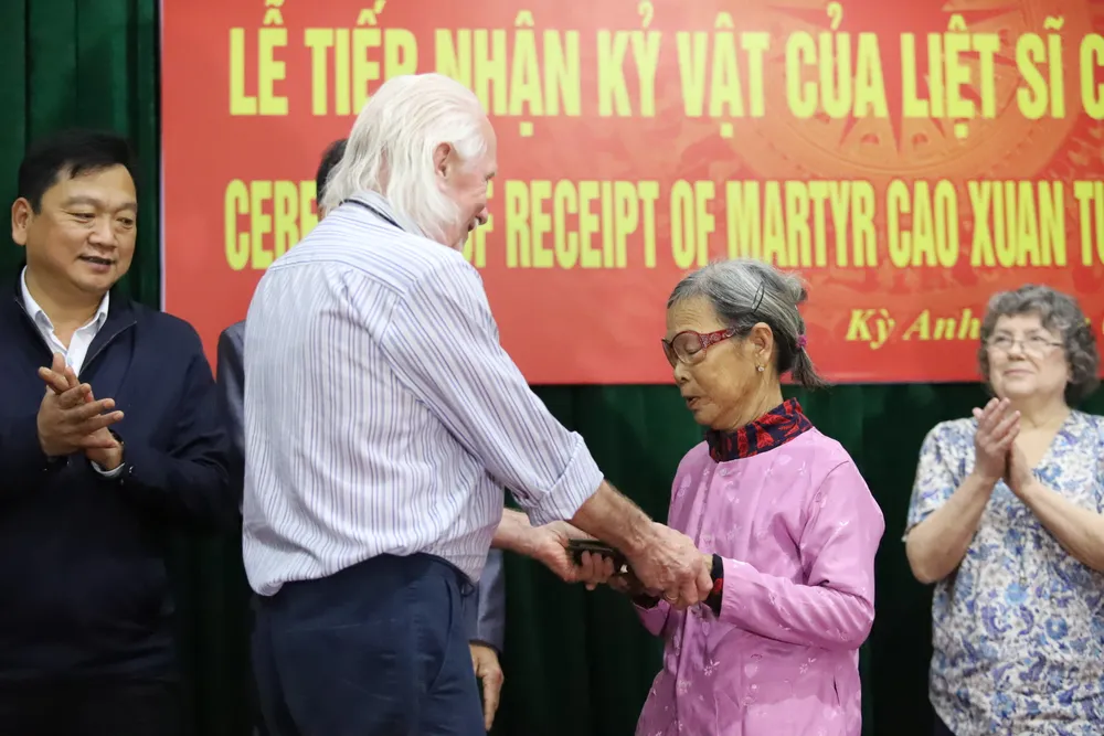 Ông Peter Mathews trao cuốn nhật ký cho bà Cao Thị Nồng (em gái liệt sĩ Cao Văn Tuất) tại hội trường xã Kỳ Xuân, huyện Kỳ Anh