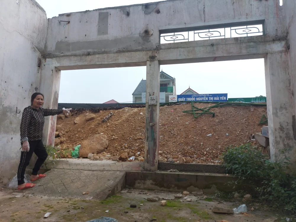 Bà Trần Thị Thanh (thôn Tân Tiến, xã Phú Lộc) từ dưới nhà chỉ tay lên Quốc lộ 15 sau khi được nâng cao. Ảnh chụp ngày 2-2-2023