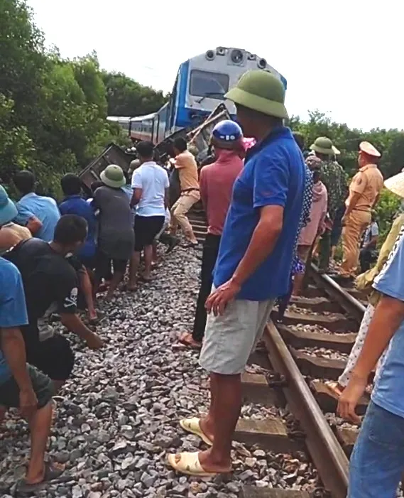 Người dân và lực lượng chức năng kéo phần đuôi xe tải ra khỏi đầu máy tàu hỏa