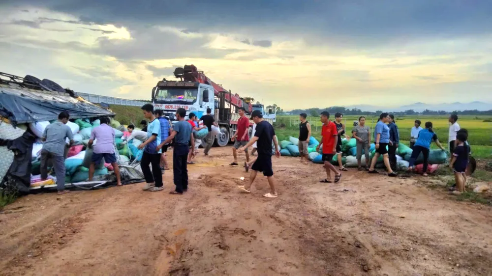 Người dân giúp đỡ tài xế bốc xếp các bao tải hàng sau tai nạn lật bên cao tốc 