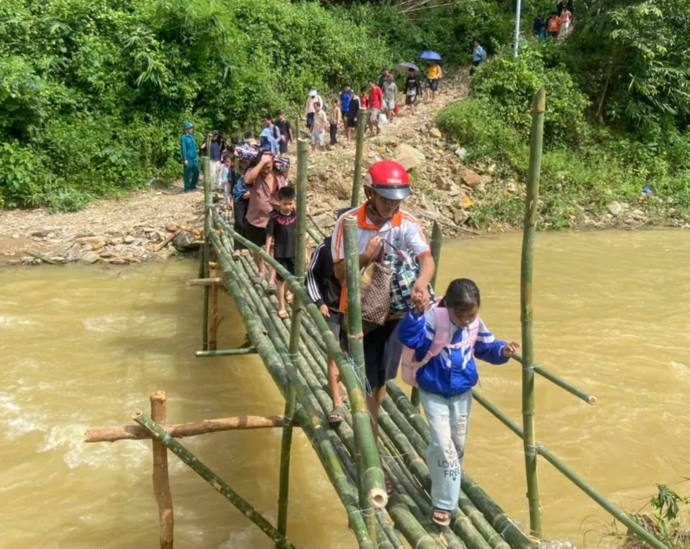 Học sinh được lực lượng chức năng hỗ trợ qua cầu tạm để kịp đến trường trong buổi học đầu tuần