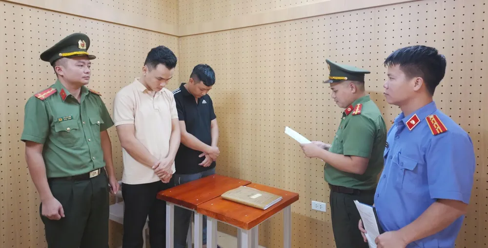 Cơ quan An ninh điều tra Công an tỉnh Hà Tĩnh tống đạt quyết định khởi tố bị can, thi hành lệnh tạm giam đối với Đặng Hoàng Lợi và Đặng Hùng Vương. Ảnh: BÙI HẢI