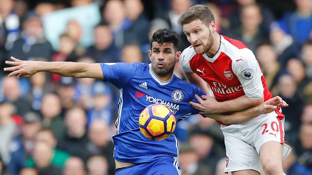 Diego Costa (trái, Chelsea) che bóng trước Shkodran Mustafi (Arsenal).