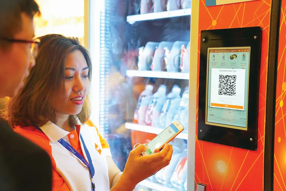 Nhờ Internet phát triển, ngày nay có thể dùng chiếc di động để thực hiện giao dịch như thanh toán ở máy bán nước tự động    Ảnh: TẤN BA