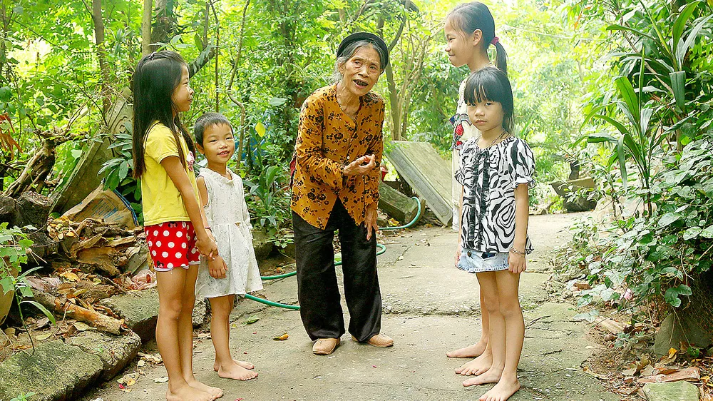 Nghệ nhân ưu tú Nguyễn Thị Vẫy dạy hát Trống quân cho thiếu nhi ngay tại vườn nhà mình