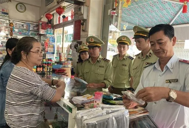 Lực lượng Quản lý thị trường kiểm tra, nhắc nhở các hiệu thuốc tân dược ký cam kết không tăng giá bán khẩu trang y tế. Ảnh: TTXVN