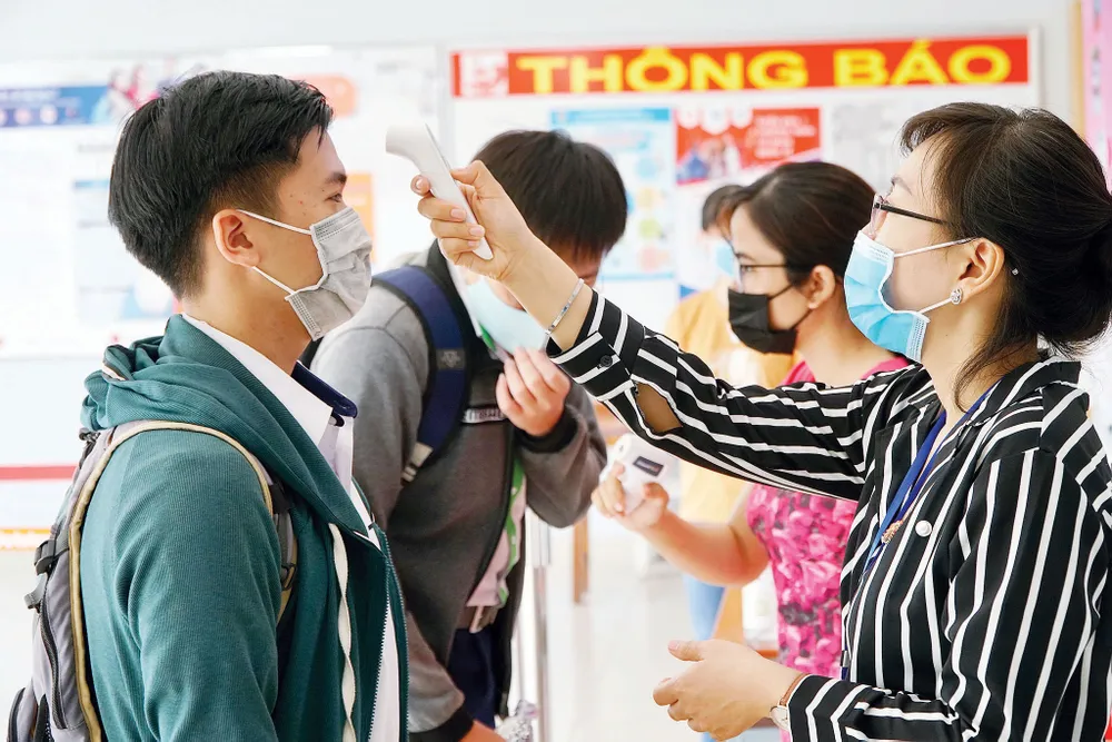 Đo thân nhiệt thí sinh tại điểm thi Trường THPT Gia Định, quận Bình Thạnh, TPHCM. Ảnh: QUANG PHÚC - HOÀNG HÙNG