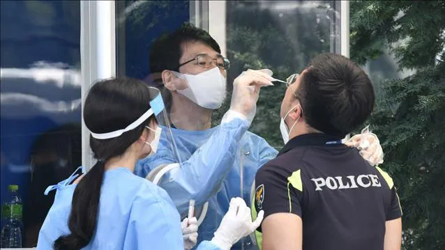  Nhân viên y tế lấy mẫu xét nghiệm COVID-19 cho một nhân viên an ninh tại Seoul, Hàn Quốc. Nguồn: TTXVN