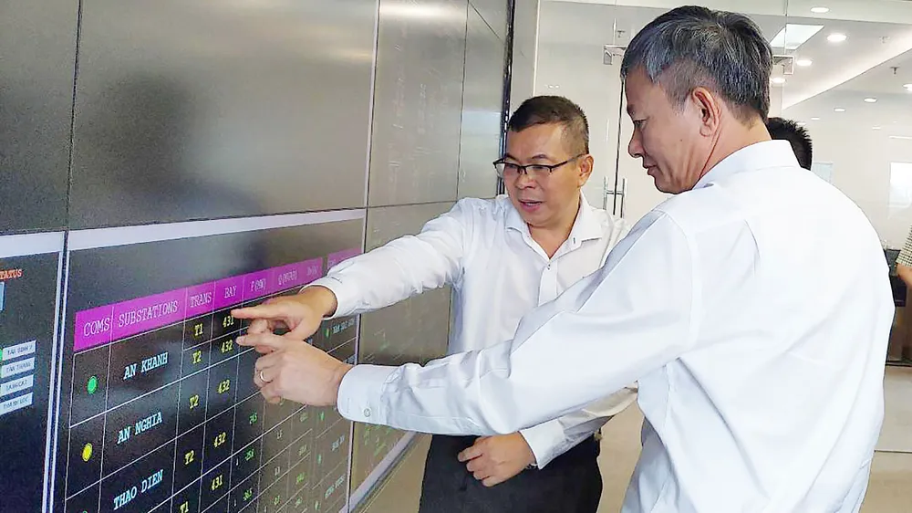 Tổng Giám đốc EVNHCMC Nguyễn Văn Thanh (bìa trái) đang báo cáo về hệ thống điều khiển từ xa tại Trung tâm Điều độ hệ thống điện TPHCM với Tổng Giám đốc EVN Trần Đình Nhân