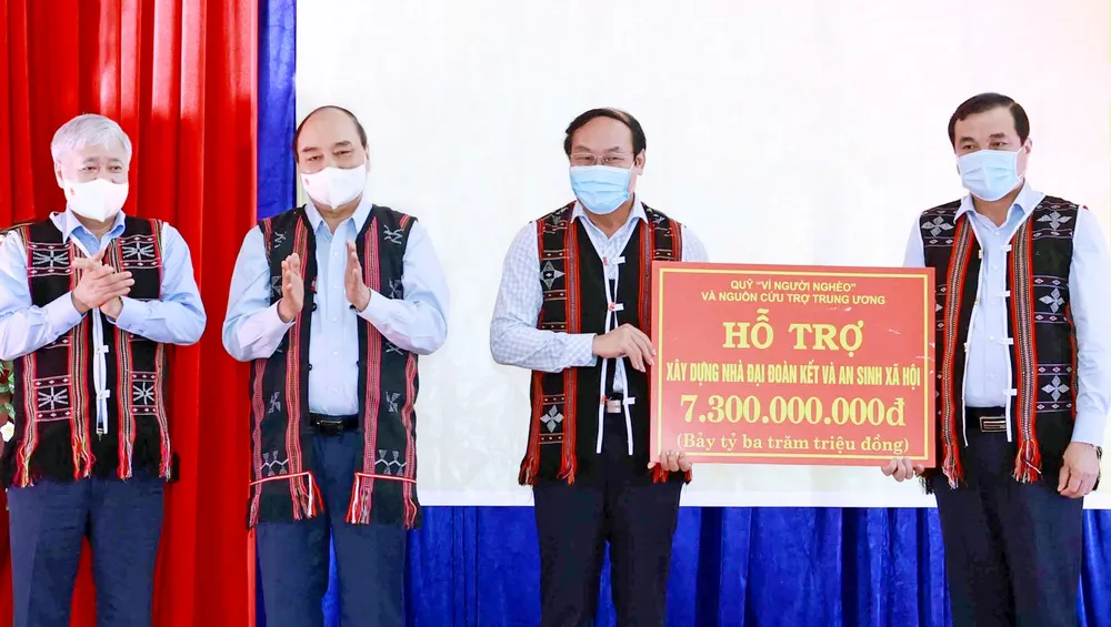 Chủ tịch nước Nguyễn Xuân Phúc chứng kiến lãnh đạo Ủy ban MTTQ Việt Nam trao số tiền xây dựng  nhà Đại đoàn kết và an sinh xã hội cho hai huyện Đông Giang và Tây Giang, tỉnh Quảng Nam. Ảnh: TTXVN