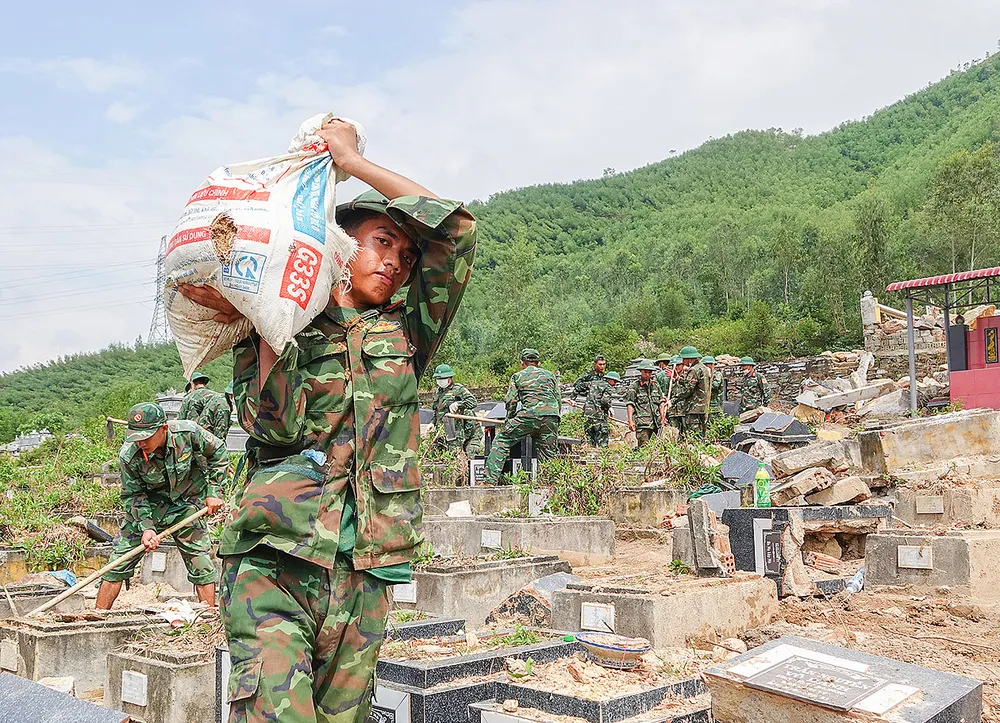 Các chiến sĩ thuộc Trung đoàn 971 (Bộ Chỉ huy Quân sự  TP Đà Nẵng) vác từng bao tải đất đá ra ngoài  để tìm mộ bị vùi lấp do sạt lở. Ảnh: XUÂN QUỲNH