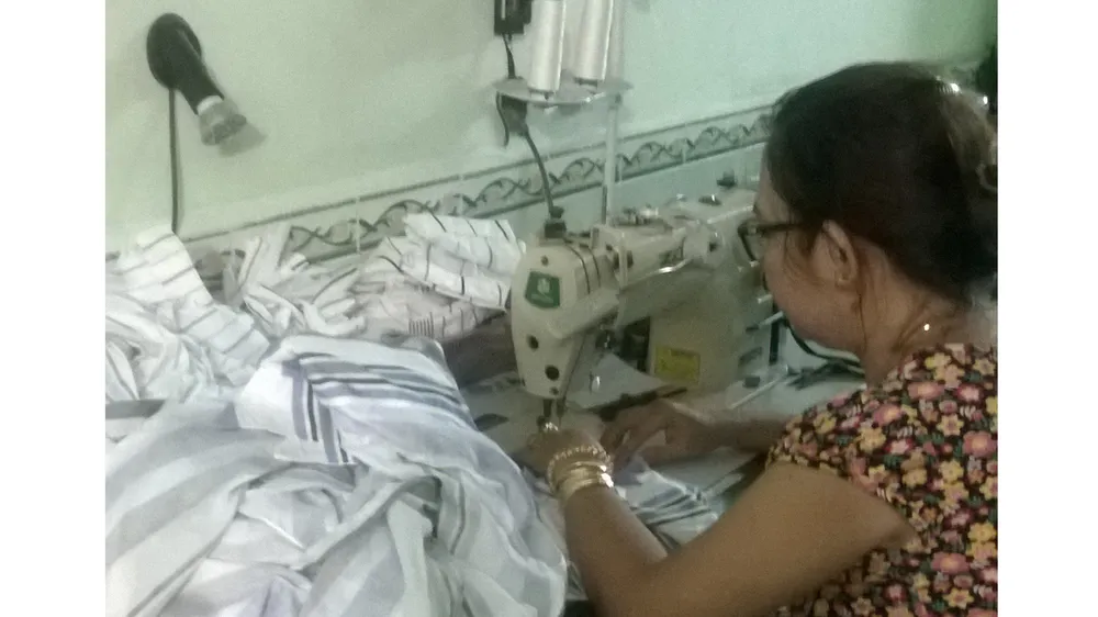 Người may gia công miệt mài làm việc để mong trang trải  cho cuộc sống gia đình