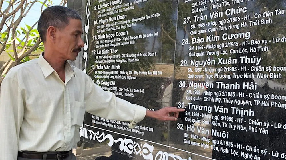 Ông Trương Văn Cẩn bên tấm bia liệt sĩ  khắc tên em trai mình